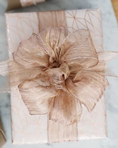 a gift wrapped in gold foil with a bow