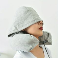 a woman wearing a gray hoodie and ear muffs with her head resting on a pillow