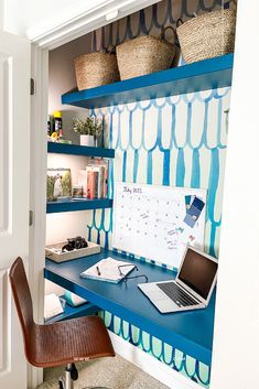 a laptop computer sitting on top of a blue shelf next to a chair and desk