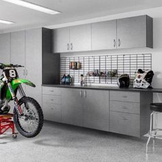 a motorcycle is parked in the middle of a garage with two stools and cabinets