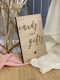 a wooden card with the words cards and gifts on it next to some dried flowers