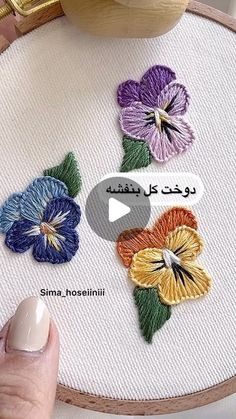 someone is stitching flowers on a piece of fabric