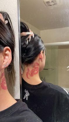 a woman with tattoos on her neck looking at herself in the mirror