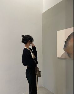 a woman standing in front of a painting and holding her hand up to her face