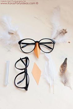 three pairs of eyeglasses and some feathers on a table