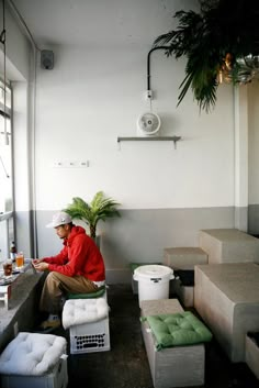 a man sitting on top of cement blocks next to a potted plant and other items