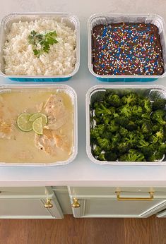 four plastic containers filled with rice, broccoli and other foods on top of a counter