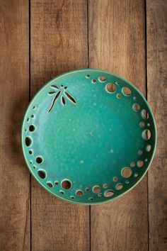 a green bowl sitting on top of a wooden table