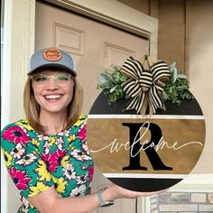 a woman holding up a wooden sign that says welcome to her family and the letter r on it