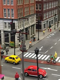 a toy city street with cars and people on bikes, pedestrians and bicyclists