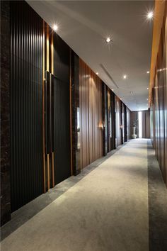 the hallway is lined with wooden paneling and lights on either side of the doors