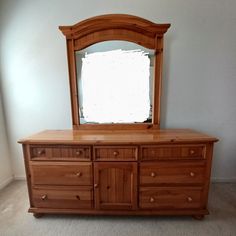 a large wooden dresser with a mirror on it's top and bottom drawers in an empty room