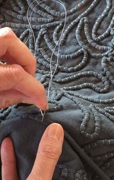 a person is stitching something on a piece of fabric with scissors and thread in their hands