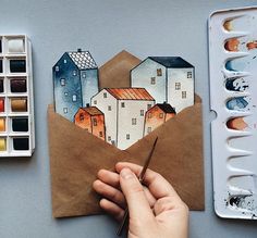 a person is drawing an envelope with watercolors and paintbrushes on the table