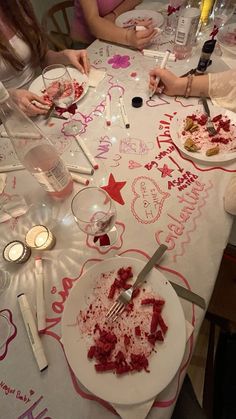 two women sitting at a table with plates of food and utensils in front of them