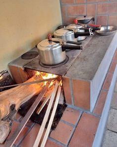 an outdoor cooking area with pots and pans on the stove top next to fire