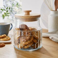 a glass jar filled with cookies on top of a wooden table