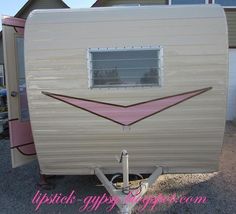 an rv parked in front of a house with a pink stripe on it's side