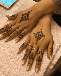 two women's hands with henna tattoos on them