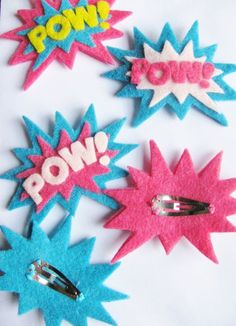 some pink and blue hair clips with the word pow on them