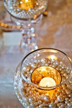 a candle that is inside of a glass bowl with pearls on the bottom and candles in it