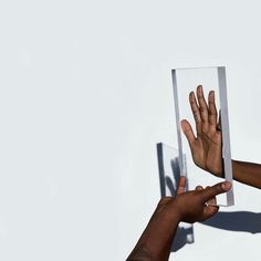 two hands reaching out to each other in front of a mirror with the reflection of someone's hand on it