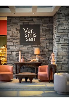 a living room filled with furniture and a stone wall next to a sign that reads ver striss sen