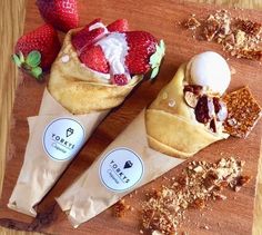 three desserts are on a cutting board with strawberries and granola in the background