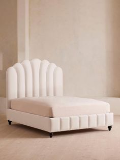 a white bed sitting on top of a hard wood floor