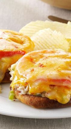 a sandwich with cheese, tomato and lettuce next to chips on a plate