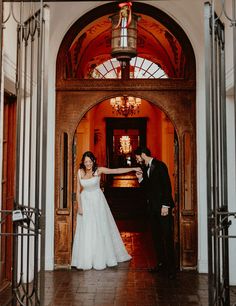 a bride and groom standing in front of an open door at their wedding reception venue