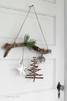 a christmas tree decoration hanging from a door with some branches and ornaments attached to it