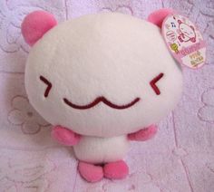 a white stuffed animal with pink ears and eyes sitting on top of a purple blanket