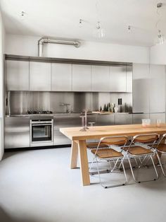 a kitchen with stainless steel appliances and wooden dining table in it's center area