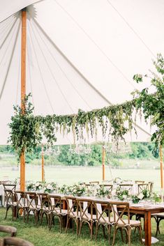 an outdoor tent with tables and chairs set up for a wedding reception in the grass