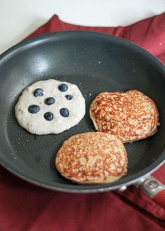 pancakes and blueberries in a frying pan on a red cloth