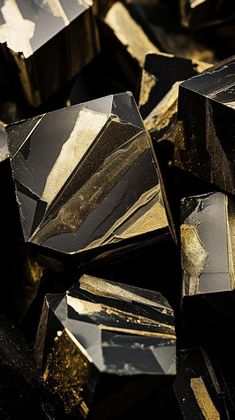 black and gold crystals are scattered on top of each other in the dark, with yellow highlights