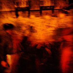 blurry photograph of people standing in front of a fence and building with red lights