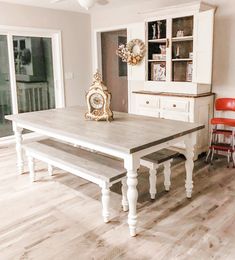 a dining room table with two benches in front of it and a clock on the wall