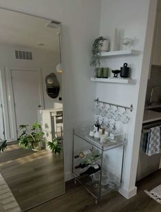 there is a glass shelf in the corner of this room with wine glasses on it