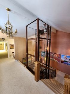 a room with some stairs and pictures on the wall behind it, in front of a chandelier