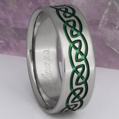 a wedding ring with an intricate design on the inside and green inlays to it