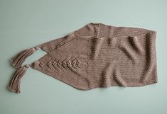 a knitted sweater with tassels on the side and a hole in the middle