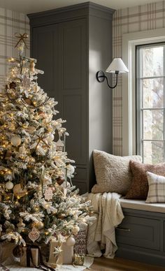 a decorated christmas tree in front of a window with white lights and ornaments on it