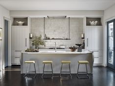 a kitchen with three stools and a center island in front of the countertop