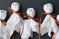 three halloween decorations made out of toilet paper with ghost faces and orange ribbon tied around them