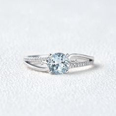 a ring with an aqua blue topaz surrounded by white diamonds on a plain surface