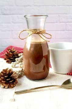 a glass jar filled with liquid sitting on top of a table next to a bowl and spoon