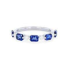 a three stone ring with blue sapphires and diamonds on the sides, set in white gold