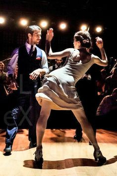 two people dancing on a wooden floor in front of an audience